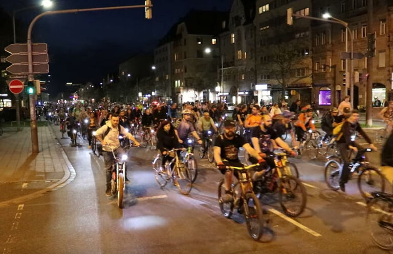 Eine große Gruppe von Radfahrenden auf der Fürther Straße in der Nacht, die auf den Betrachter zufahren