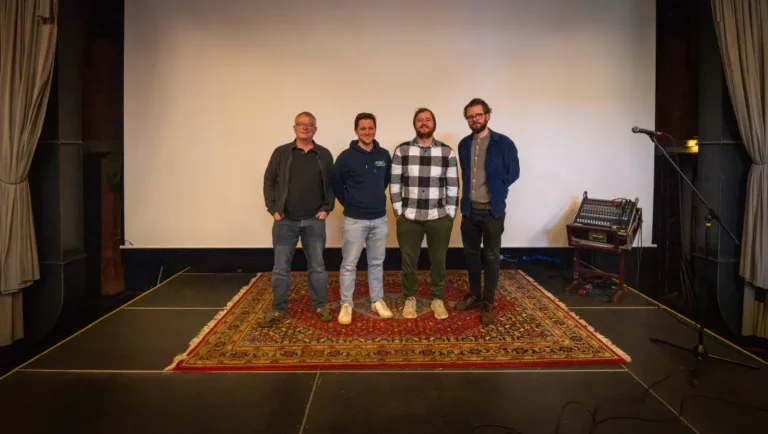 Vier Männer auf einer Bühne mit Teppich